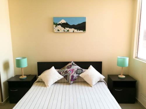 TocancipáAparta hotel TOCANCIPA con Parqueadero y Wifi的一间卧室配有一张带两盏灯的床,墙上挂着一张照片