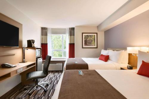 莱迪史密斯Microtel Inn & Suites by Wyndham Oyster Bay Ladysmith的酒店客房配有两张床和一张书桌
