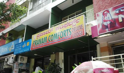 班加罗尔PRANAM COMFORTS LODGE的前面有标志和伞的建筑