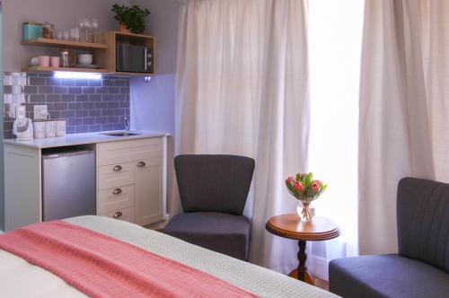 西萨默塞特Brookshill - Protea suite的一间卧室配有一张床、两把椅子和一张桌子