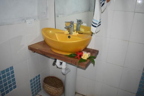 塔纳岛奥法海滩简易别墅的浴室的木架上有一个黄色的水槽