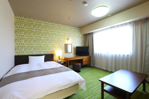 八户市八户大酒店的一间卧室设有一张床、一台电视和一个窗口。