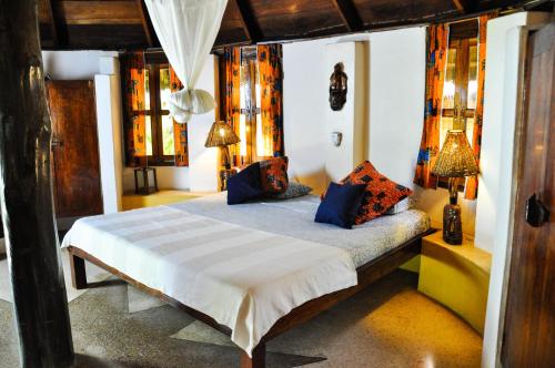 Axim安考布拉海滩度假酒店的一间卧室配有一张带蓝色枕头的床