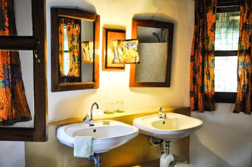 Axim安考布拉海滩度假酒店的浴室设有两个水槽和墙上的镜子