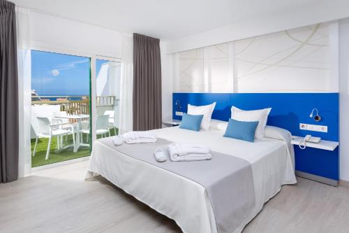 阿德耶PlayaOlid All Inclusive的卧室配有一张蓝色色调的大型白色床。