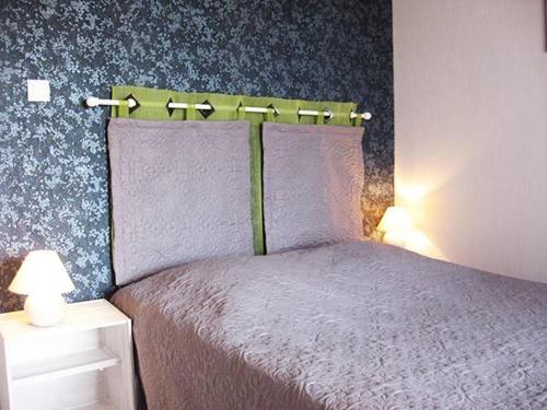 RetournacLes Frênes的一间卧室配有一张带紫色床单和蓝色壁纸的床