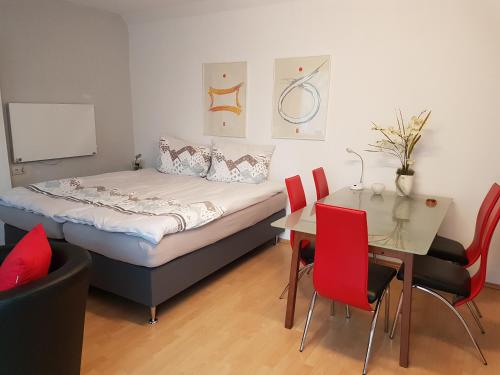 措伊滕Zeuthen Ferienwohnung am See, Stadtgrenze Berlin的一间卧室配有一张床和一张桌子及红色椅子