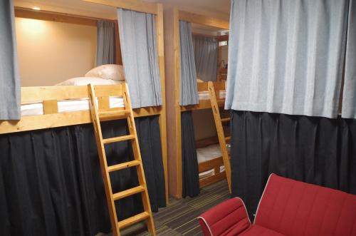 广岛Guesthouse POPTONE的宿舍间设有两张双层床和一把椅子。
