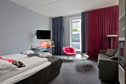 奥斯陆Thon Partner Hotel Ullevaal Stadion的酒店客房,配有一张床和一张红色椅子