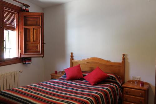 卡皮雷拉Apartamentos Rurales Rosendo: El Orégano的一间卧室配有一张带红色枕头的床和一扇窗户