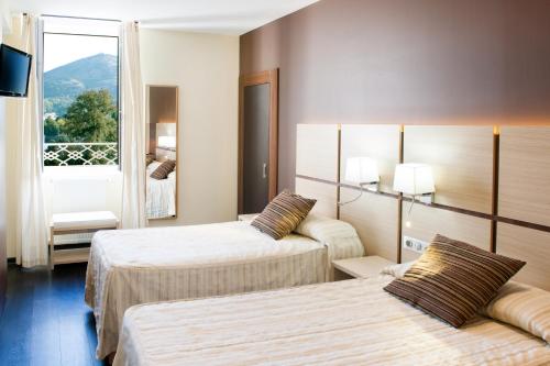卢尔德菈桑斯酒店的酒店客房设有两张床和窗户。