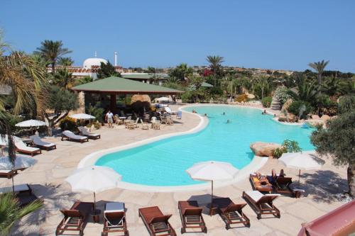 兰佩杜萨Cupola Bianca Resort的度假村的游泳池,配有椅子和遮阳伞