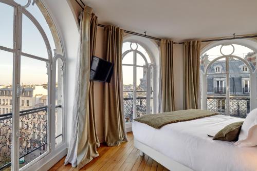 巴黎Tinah Paris, Réaumur - Montorgeuil的一间卧室设有一张床和两个大窗户