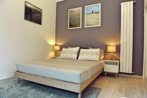 佛罗伦萨Domus Plaza的一间卧室配有一张带两盏灯的床,墙上有两张照片