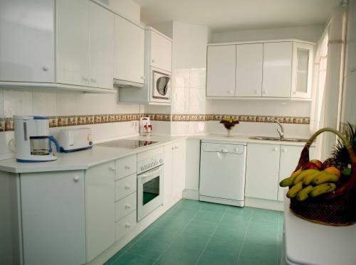 Estepona米格尔安赫尔公寓的一间铺有绿色地板并配有白色橱柜的厨房