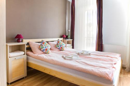 米什科尔茨MSE Apartman的一间卧室配有带粉红色枕头的床和窗户。