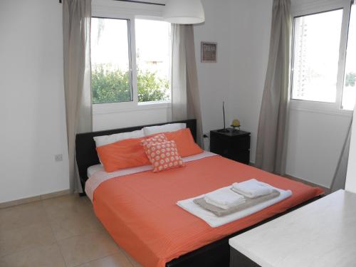 帕拉利米尼Cosy apartment in a luxury resort的一间卧室配有带橙色床单和枕头的床。