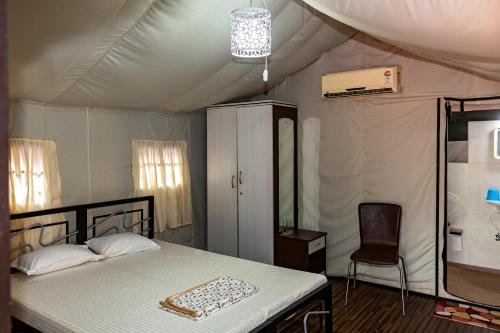 达博利Tent-O-Treat Premium Rooms near Dapoli的一间卧室配有一张床铺,帐篷内提供一把椅子