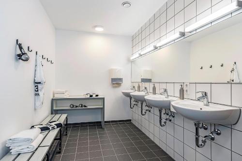 阿尔滕霍尔茨Hotel Athletik Kiel的浴室设有3个水槽和一排镜子