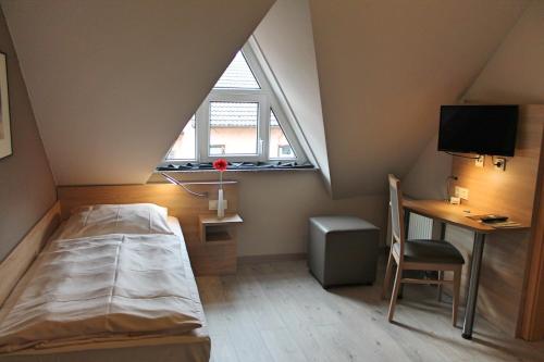 陶努斯山麓霍夫海姆古鲁奈沃德酒店的一间卧室配有一张床、一张书桌和一个窗户。