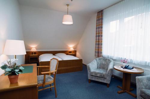 埃姆登Hotel Delfthalle的酒店客房带一张床、一张桌子和椅子