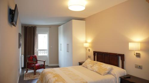 卢戈Apartamento Vía Romana XIX的卧室配有床、椅子和窗户。