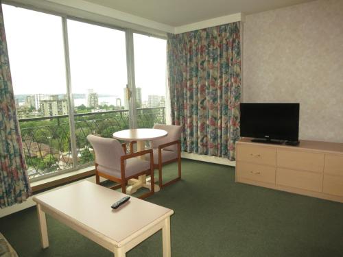 温哥华琼碧卡纳套房酒店的客厅配有桌子、电视和窗户。