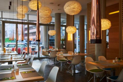 柏林Grimm's Berlin Mitte的一间带桌椅和灯光的餐厅