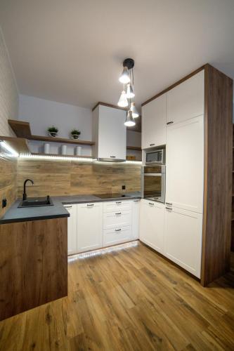 比得哥什Apartament Gdańska的厨房铺有木地板,配有白色橱柜。