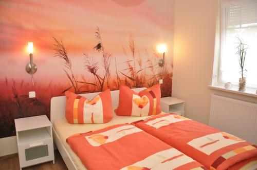 马林费尔德Ferienhaus Müritzzauber / EG-Appartement的一间卧室配有带橙色和白色枕头的床