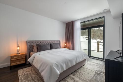 蒙特朗布朗Horizon 104 by Tremblant Prestige的一间卧室设有一张大床和一个大窗户