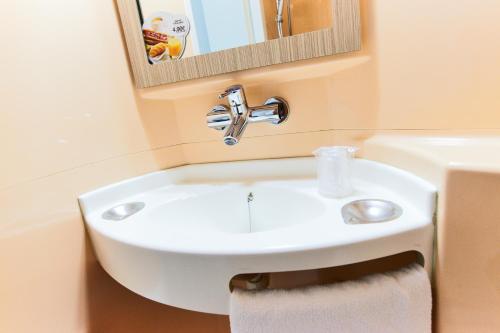 鲁瓦西昂法兰西戴高乐机场-巴黎北部维勒班特展览中心普瑞米尔经典酒店的浴室设有白色水槽和镜子
