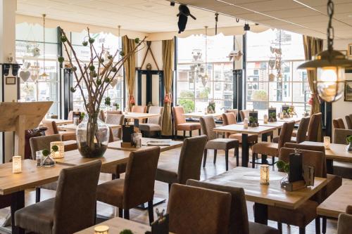 沃尔克姆金狮大酒店的餐厅设有木桌、椅子和窗户。