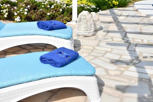 帕罗奇亚Villa Trifylia的庭院里配有两把带蓝色靠垫的白色柳条椅