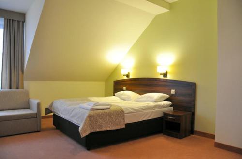 MniówHotel Dudek的配有一张床和一把椅子的酒店客房