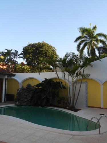 亚松森Hotel Casa Jardin的棕榈树建筑前的游泳池