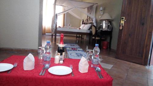 达累斯萨拉姆Serene Hotel的一张红色桌子,上面放有盘子和酒瓶