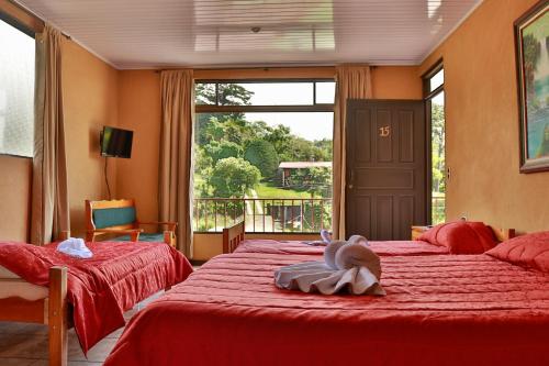 蒙泰韦尔德哥斯达黎加卡比纳斯艾迪住宿加早餐旅馆的一间卧室设有两张带红色床单的床和窗户。