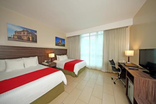 巴拿马城Victoria Hotel and Suites Panama的酒店客房设有两张床和一台平面电视。