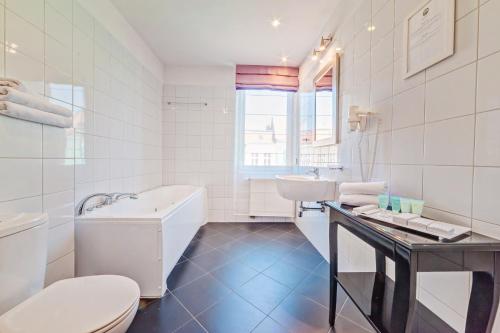 波兹南丹普雷斯提齐酒店的白色的浴室设有浴缸、盥洗盆和卫生间。