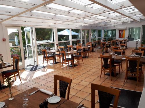 斯泰厄Møn Golf Resort - Hotel Præstekilde的一间空餐厅,配有木桌和椅子