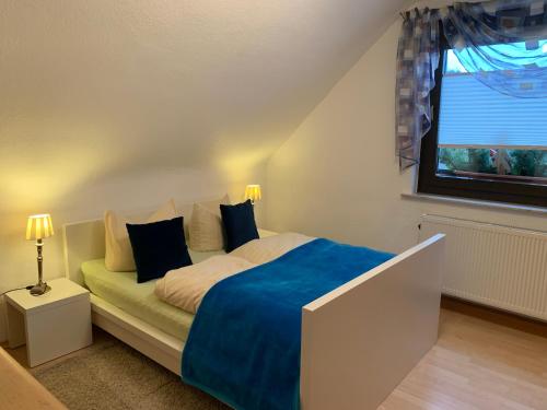 SchleusingenFerienhaus zur Waldauer Höhe mit 3 SZ, 120qm & 40qm Balkon的一间卧室配有一张带蓝色床单的床和一扇窗户。