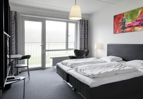 EjbyFjelsted Skov Hotel & Konference的卧室配有床、椅子和窗户。