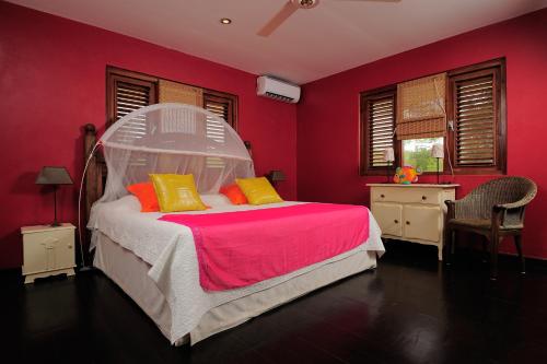 克拉伦代克Casa El Tropico的一间卧室配有白色的床、红色的墙壁和黄色的枕头