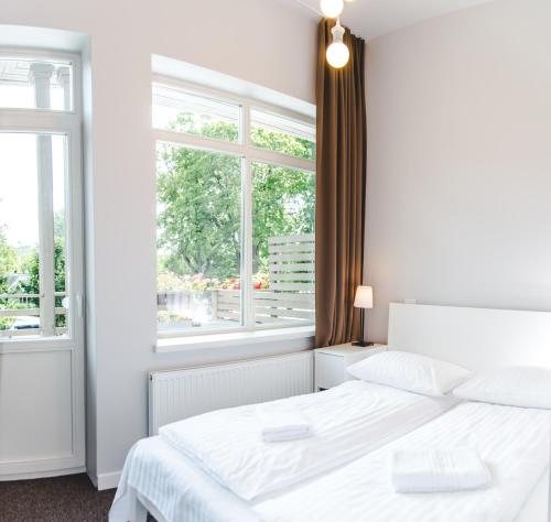 德鲁斯基宁凯豪斯旅馆的白色的卧室设有白色的床和窗户。