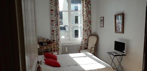 昂热Chambre d'Hôtes Marchand的一间卧室配有一张带红色枕头的床和一扇窗户