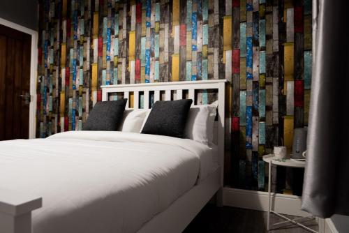 曼彻斯特REM酒店的卧室配有白色的床和色彩缤纷的壁纸