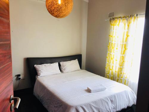 哈博罗内Villa 134 Modipane的卧室配有白色床和黄色窗帘