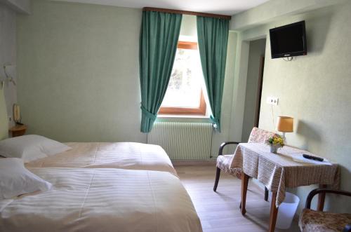 Dabo孚日之家酒店的一间卧室配有一张床、一张桌子和一个窗户。