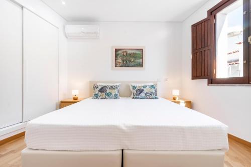 塔维拉Apartamento 1º de Maio的白色卧室配有一张带两个枕头的大床
